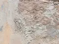 Texture d'un mur extérieur dégradé, montrant des zones de salpêtre et d'enduit écaillé, une cause visible de détérioration.