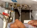Fuite d'eau par le haut du chauffe-eau, près d'un joint rouge. Un filet d'eau s'échappe des raccords métalliques.