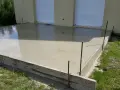 Dalle en béton fraîchement coulée pour une maison, avec coffrage en bois et ferraillage apparent. L'épaisseur de la dalle est visible.