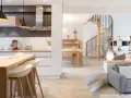 Cuisine moderne avec îlot, escalier hélicoïdal et salon. Cette maison, aux caractéristiques des années 70, allie confort et design.