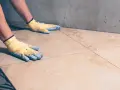 Pose de carrelage avec des gants, assurant l'étanchéité sur carrelage existant.