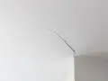 Fissure visible sur un joint de placo au plafond, indiquant la nécessité de réparer.