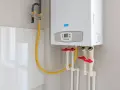 Installation d'un ballon d'eau chaude Baxi. Tuyaux de gaz et d'eau avec robinets rouges.