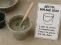 Préparation du béton : un seau de ciment, du sable, du gravier et de l'eau sont prêts à être mélangés.