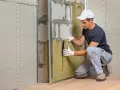 Pose d'isolant dans un mur intérieur de maison ancienne. Un ouvrier installe la laine de roche dans une ossature métallique avant la pose des plaques de plâtre.