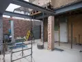 Travaux de rénovation : agrandir ouverture mur porteur avec poutres métalliques. Échafaudages, briques et outils sur le chantier.