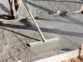 Un ouvrier lisse le béton frais pour créer une pente de terrasse.