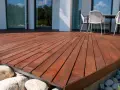 Belle terrasse en bois sur plot, avec des meubles de jardin et des rochers.