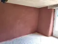Un coin de pièce aux murs recouverts d'un enduit chaux sable ocre. Le sol est protégé par une bâche. Le plafond est en bois clair.