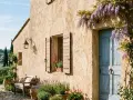 Maison de campagne avec enduit à la chaux extérieur, porte bleue, volets en bois, banc et lavande.