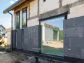Maison en construction avec panneaux de polystyrène gris fixés pour le ravalement et isolation extérieure.