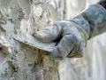 Main tenant utilise une spatule pour comment reboucher une fissure dans un mur.