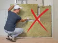 Un ouvrier installe un isolant bruit mur. Une croix rouge indique une mauvaise pose.