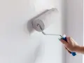 Main d'homme appliquant de la peinture blanche sur un mur avec un rouleau. Un guide visuel pour comment peindre un mur.