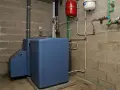 Chaudière fioul bleue dans une chaufferie, avec réservoirs rouge et blanc. Le prix du chauffage fioul est une préoccupation.