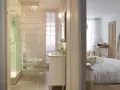 Salle de bain moderne avec douche, lavabo et toilettes, séparée de la chambre par un mur en brique de verre.