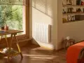 Radiateur blanc mural, discret et efficace, diffusant une chaleur douce grâce à son fluide caloporteur. Un coin bureau et un lit douillet complètent cette pièce chaleureuse.