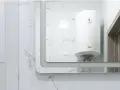 Gros chauffe-eau blanc, une chaudière micro accumulation, reflété dans un grand miroir, sur fond de carrelage marbré.