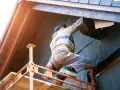 Un ouvrier sur un échafaudage installe l'isolation extérieur facade d'une maison, protégeant la structure en bois.