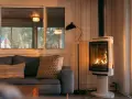 Un poêle à bois moderne, avec un feu vif, est placé à distance du mur en placo, créant une ambiance chaleureuse.