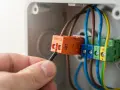 Main électrique pour brancher radiateur inertie sur prise de courant. Connexion des fils dans un boîtier.