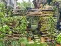 Une **pose brise vue** naturelle et luxuriante, faite de bois flotté et de plantes grimpantes, avec un miroir reflétant un paysage verdoyant.