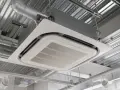 Unité de climatisation par le plafond, discrète et efficace, intégrée dans un faux plafond avec des conduits d'air apparents.