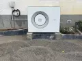 Unité extérieure d'une chaudière à condensation Bosch, installée sur des blocs de béton, avec un chargeur mural à proximité.