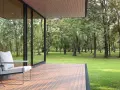 Une terrasse moderne avec un revêtement de terrasse en résine, offrant une vue paisible sur une forêt verdoyante. Un fauteuil confortable invite à la détente.