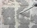 Outil de burinage en action pour enlever colle carrelage sur un mur en béton.