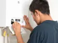 Un technicien ajuste une chaudière à condensation. L'installation est en cours, assurant un chauffage efficace.