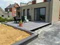 Une terrasse moderne en cours de création, avec des dalles grises surélevées par des plots. Un espace extérieur prêt à être aménagé.