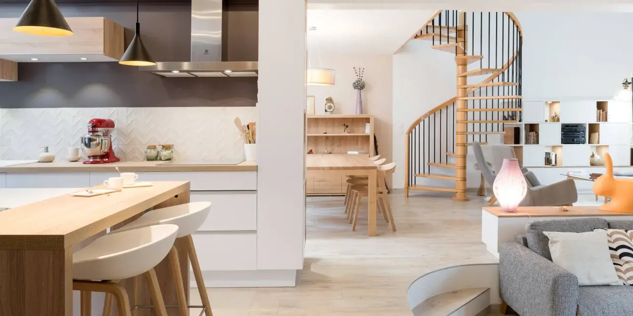Cuisine moderne avec îlot, escalier hélicoïdal et salon. Cette maison, aux caractéristiques des années 70, allie confort et design.