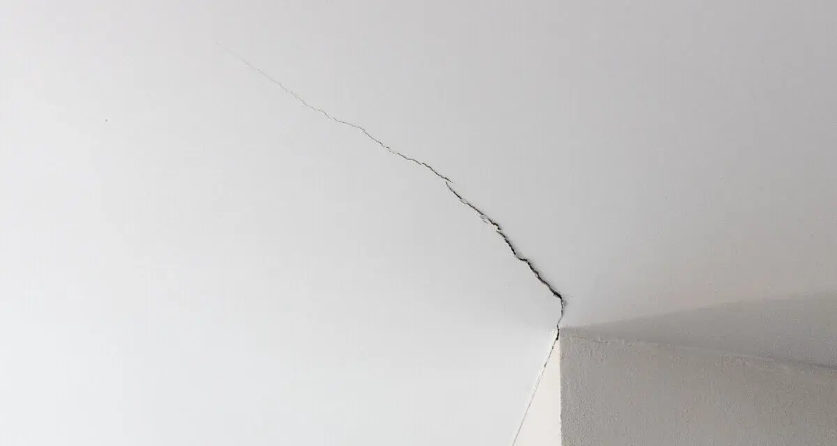 Fissure visible sur un joint de placo au plafond, indiquant la nécessité de réparer.