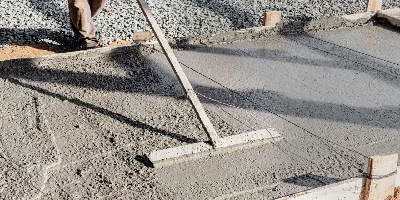 Un ouvrier lisse le béton frais pour créer une pente de terrasse.