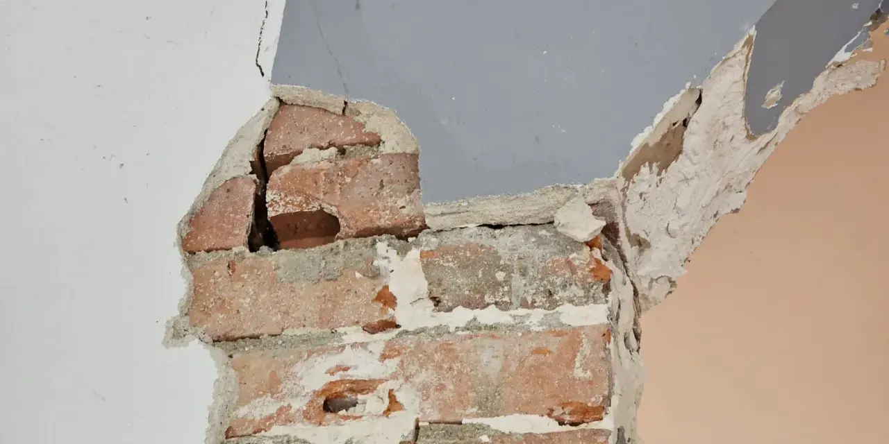 Fissures dans un mur de briques, signe d'une **stabilisation fondation maison sol argileux** nécessaire.