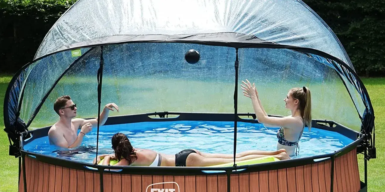 Trois personnes jouent dans une piscine hors sol sous un abri transparent. Idéal pour savoir comment fabriquer un abri piscine hors sol.