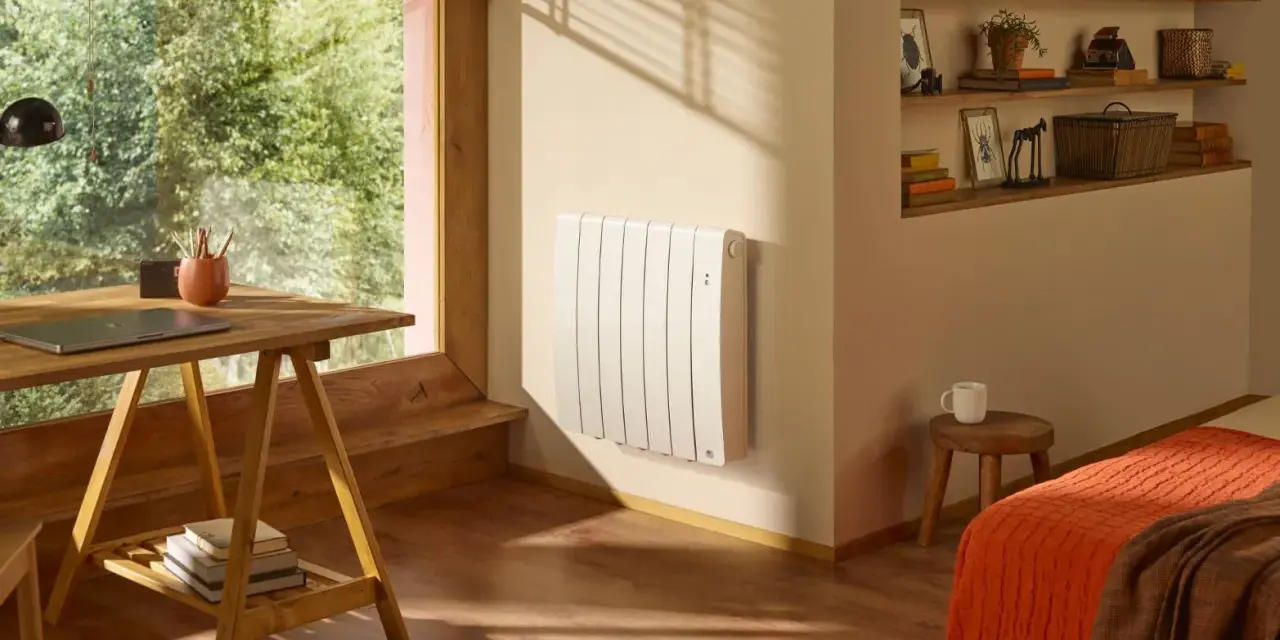 Radiateur blanc mural, discret et efficace, diffusant une chaleur douce grâce à son fluide caloporteur. Un coin bureau et un lit douillet complètent cette pièce chaleureuse.