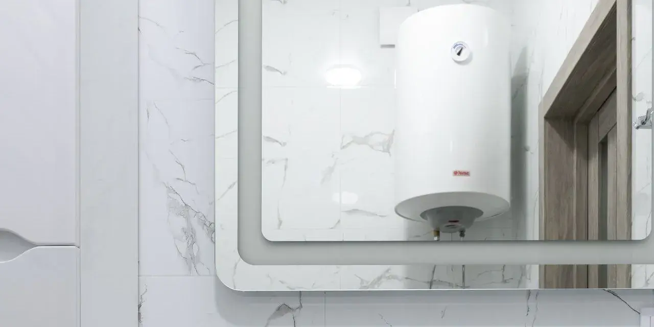 Gros chauffe-eau blanc, une chaudière micro accumulation, reflété dans un grand miroir, sur fond de carrelage marbré.