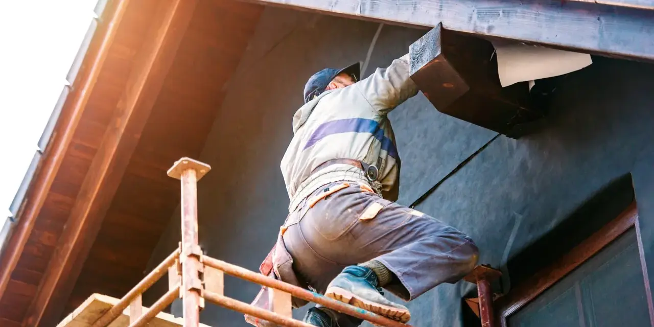 Un ouvrier sur un échafaudage installe l'isolation extérieur facade d'une maison, protégeant la structure en bois.