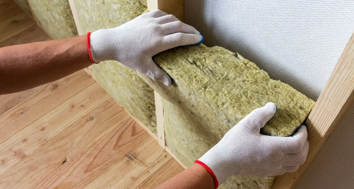 Mains gantées installent un isolant pour aider à isoler un mur humide.