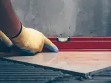 Pose d'un carrelage avec un niveau à bulle pour vérifier l'épaisseur du carrelage et de la colle.