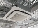Unité de climatisation par le plafond, discrète et efficace, intégrée dans un faux plafond avec des conduits d'air apparents.