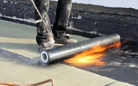 Pose d'une membrane bitumineuse sur une terrasse. Le prix de l'étanchéité d'une terrasse carrelée dépend de la technique utilisée.