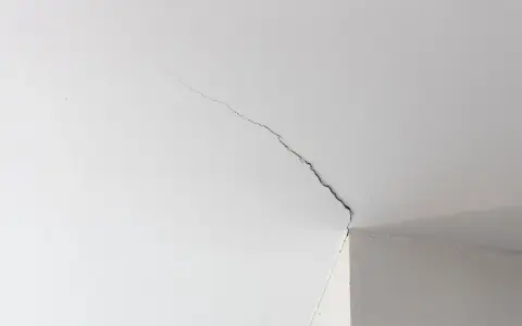 Fissure visible sur un joint de placo au plafond, indiquant la nécessité de réparer.