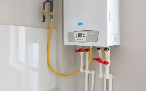 Installation d'un ballon d'eau chaude Baxi. Tuyaux de gaz et d'eau avec robinets rouges.