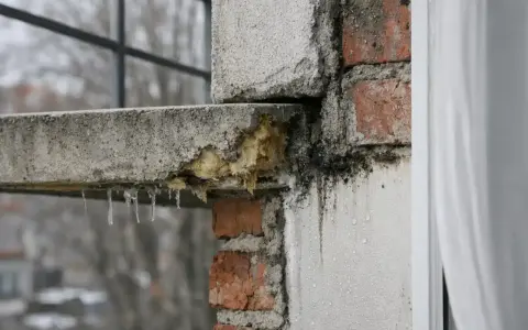 Détérioration d'un balcon en béton, avec des stalactites de glace et des traces de moisissure. Un pont thermique favorise la condensation et la dégradation.