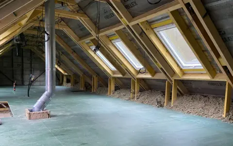 Aménagement des combles d'une maison Phénix : charpente, fenêtres de toit, isolation et gaine de ventilation en cours.