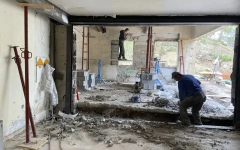 Travaux de démolition en cours pour une aide à la rénovation maison ancienne. Des ouvriers utilisent des outils pour casser le béton.