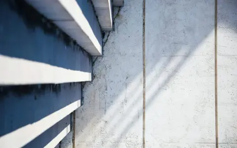 Ombre et lumière sur un mur en béton cellulaire, texture brute et lignes architecturales.